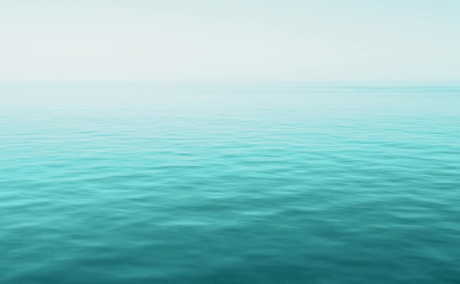 Calm turquoise ocean water meeting clear sky at horizon